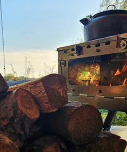 Cocina Bushcraft de Leña encendida al aire libre con troncos listos para usar.